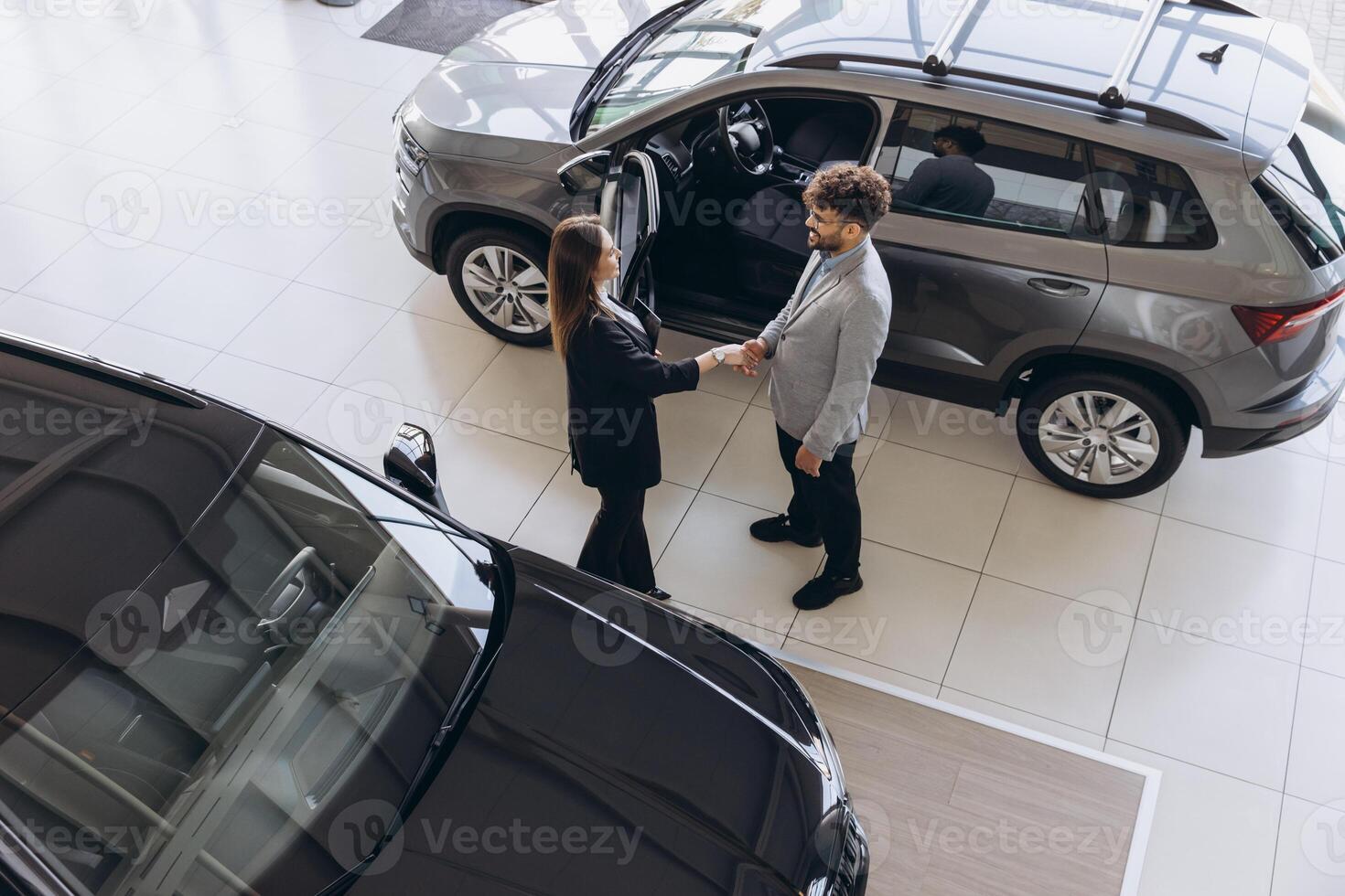 Salesperson shaking hands with customer after selling a car in a dealership photo