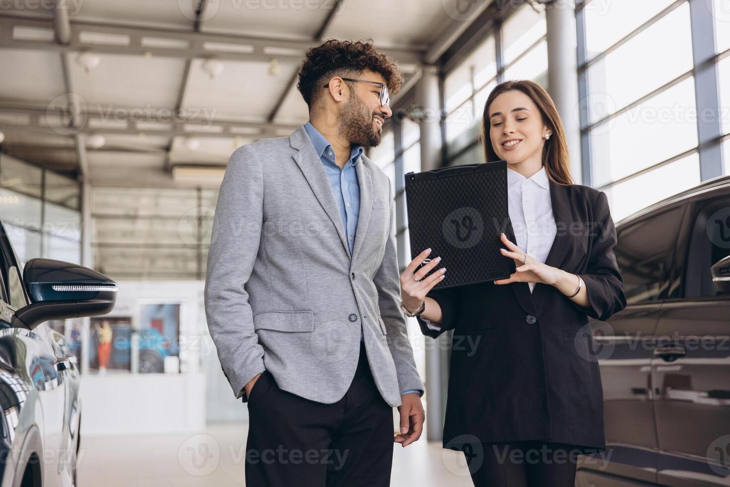Car salesperson showing new vehicle to customer in dealership photo