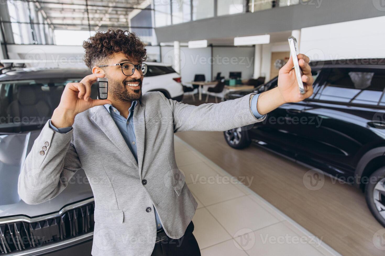 Happy Man Taking Selfie Showing New Car Key in Dealership photo