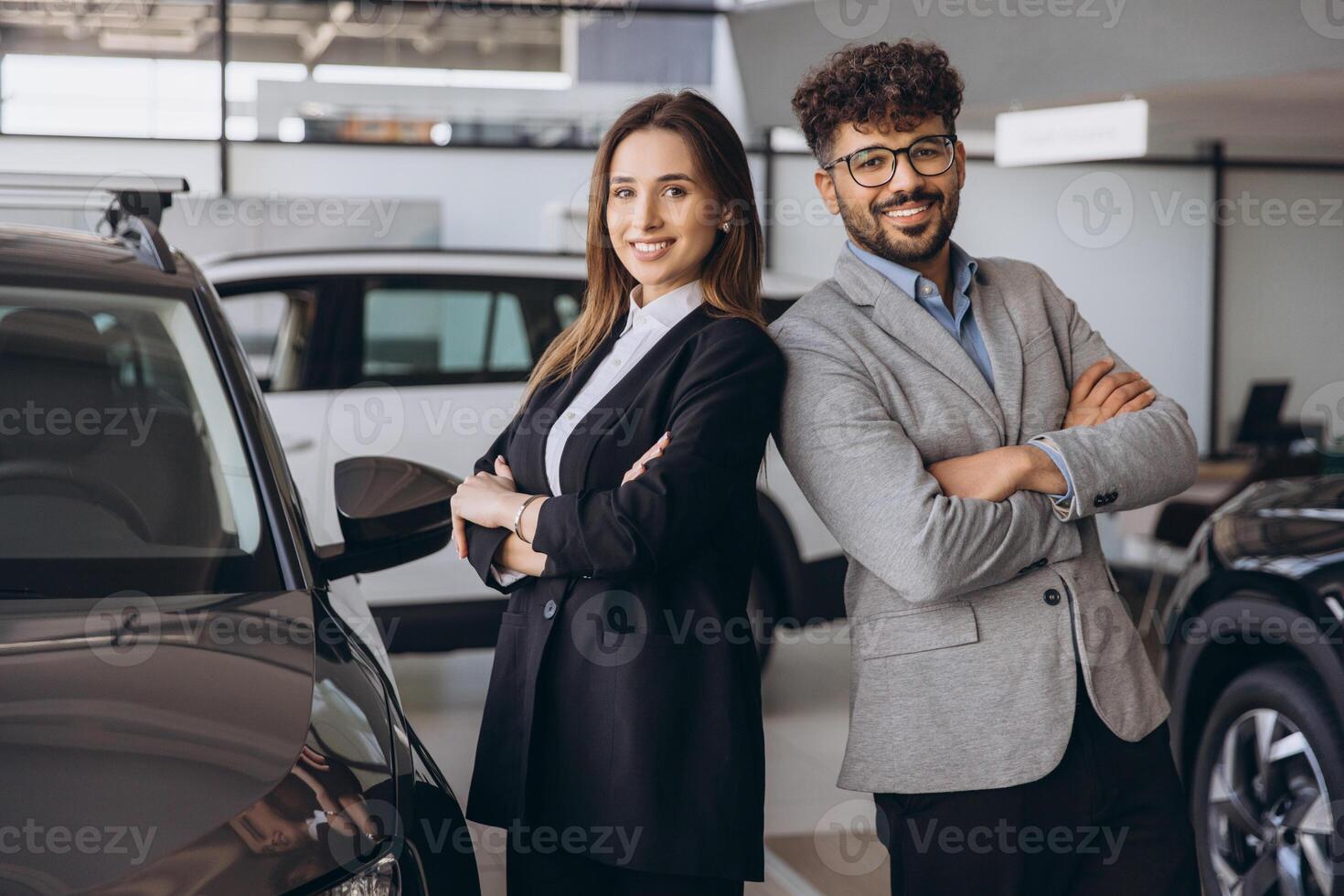 Salespeople standing back to back in a car showroom dealership photo
