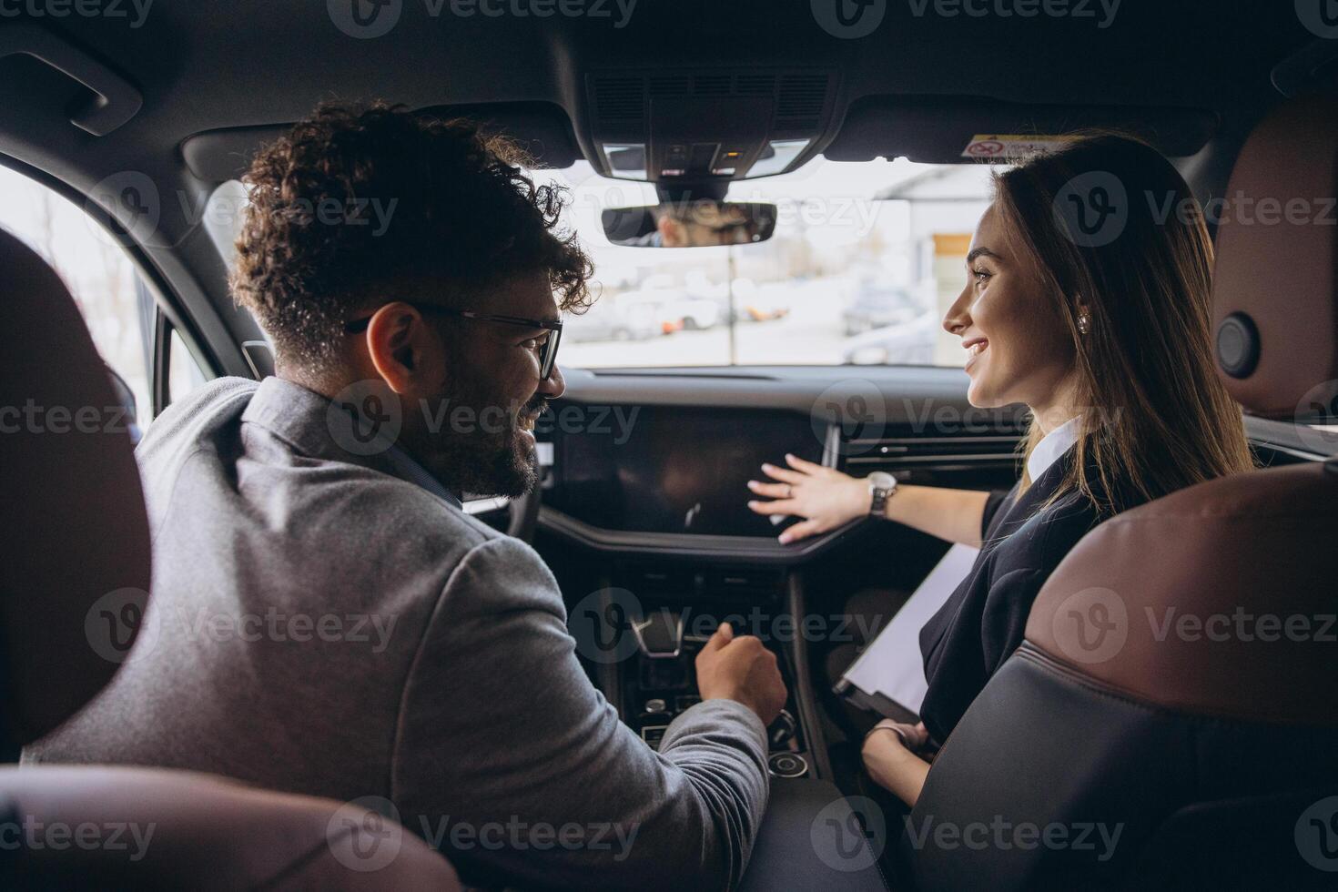 Car dealer showing new car features to customer in car dealership photo