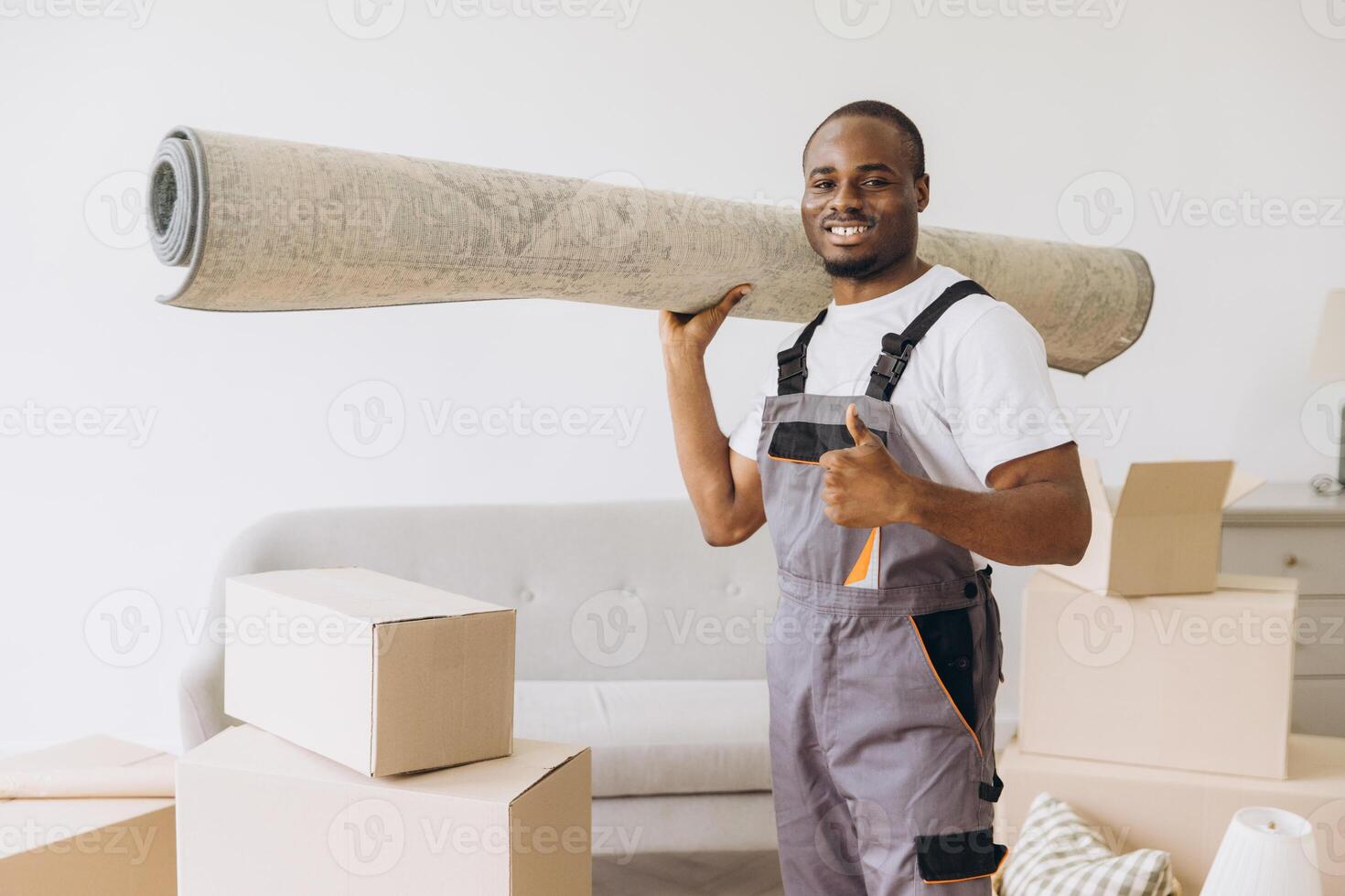 African american mover carrying rolled up carpet and gesturing thumbs up during home moving photo