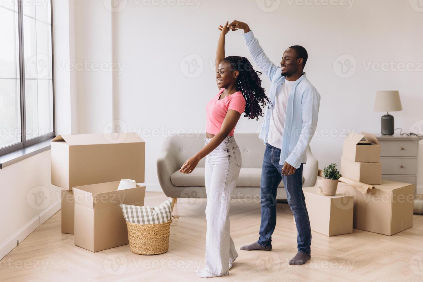 Happy african american couple dancing in new apartment during moving day photo
