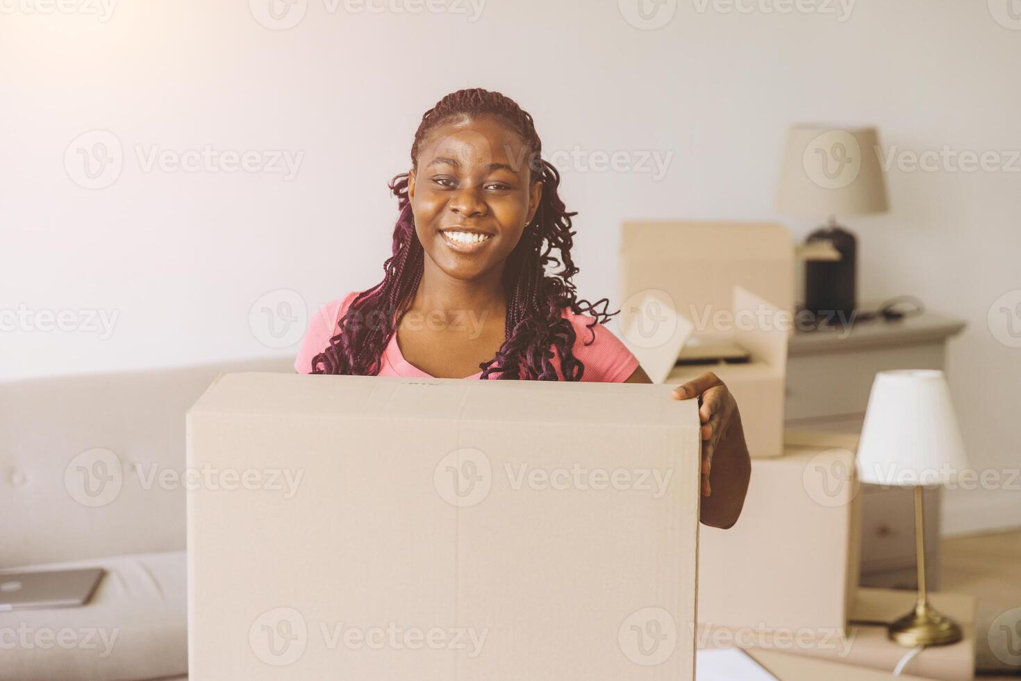Young african american woman moving house holding cardboard box smiling photo
