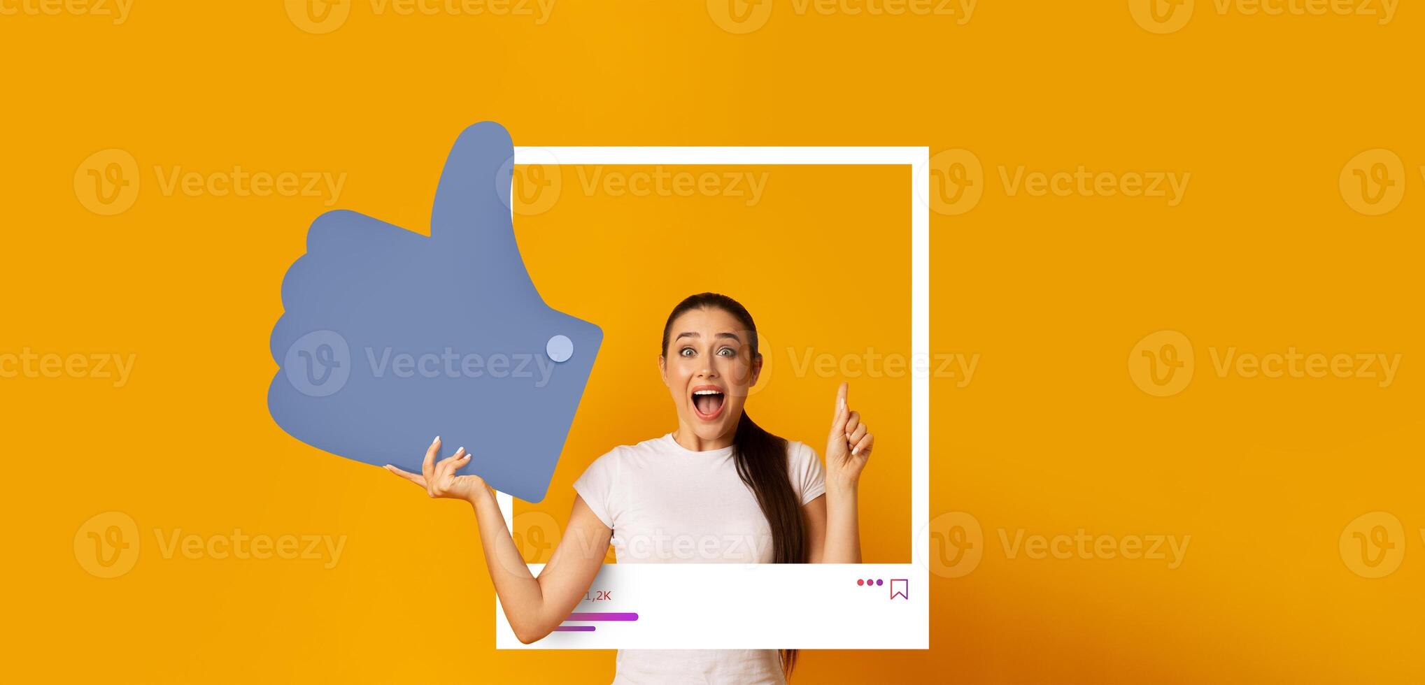 A young woman joyfully gives a thumbs up while posing in front of a bright yellow background. She appears enthusiastic about sharing content on social media, engaging her audience. photo