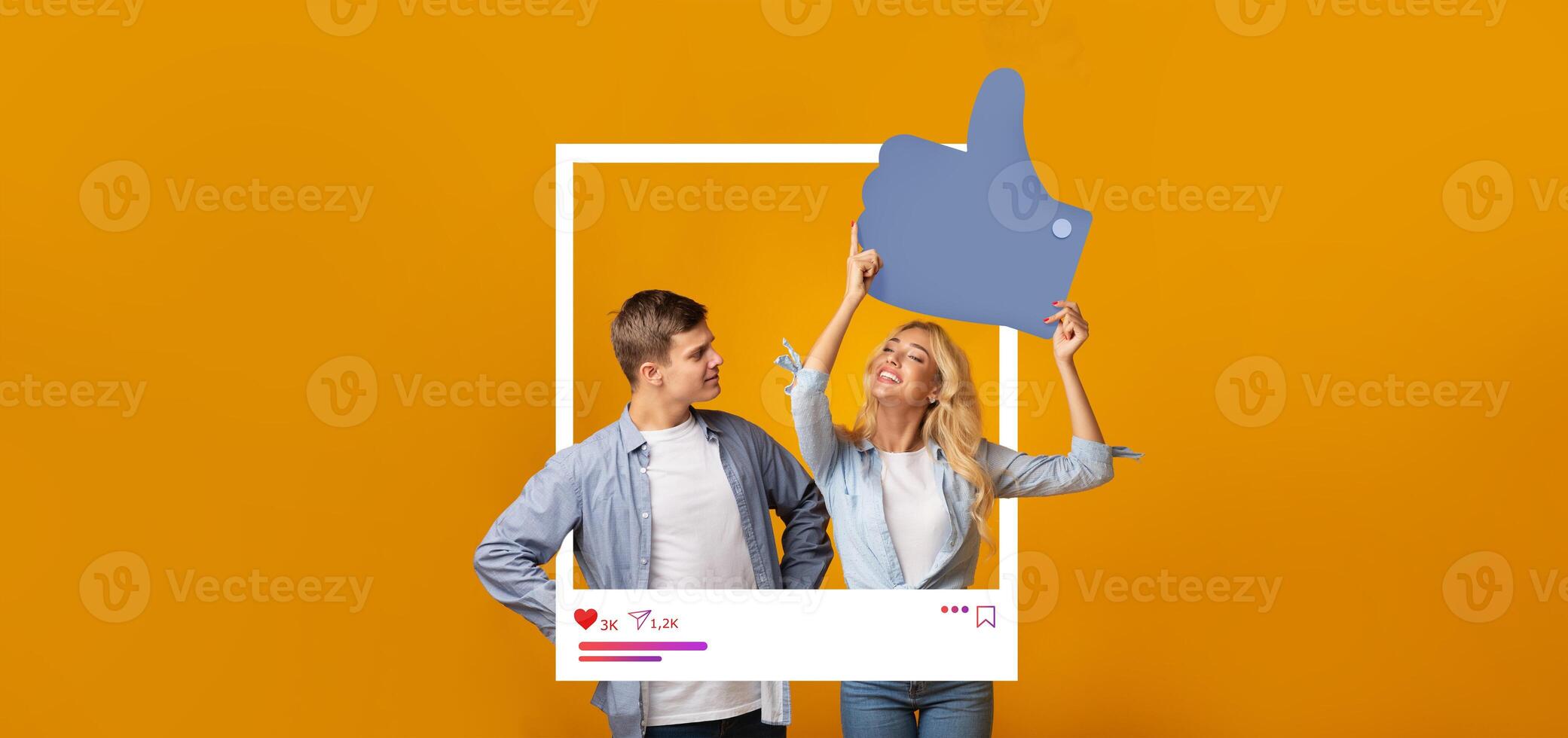 Two young individuals stand against a vibrant orange backdrop, joyfully showcasing a large thumbs-up symbol. They embody the spirit of online engagement and content creation. photo