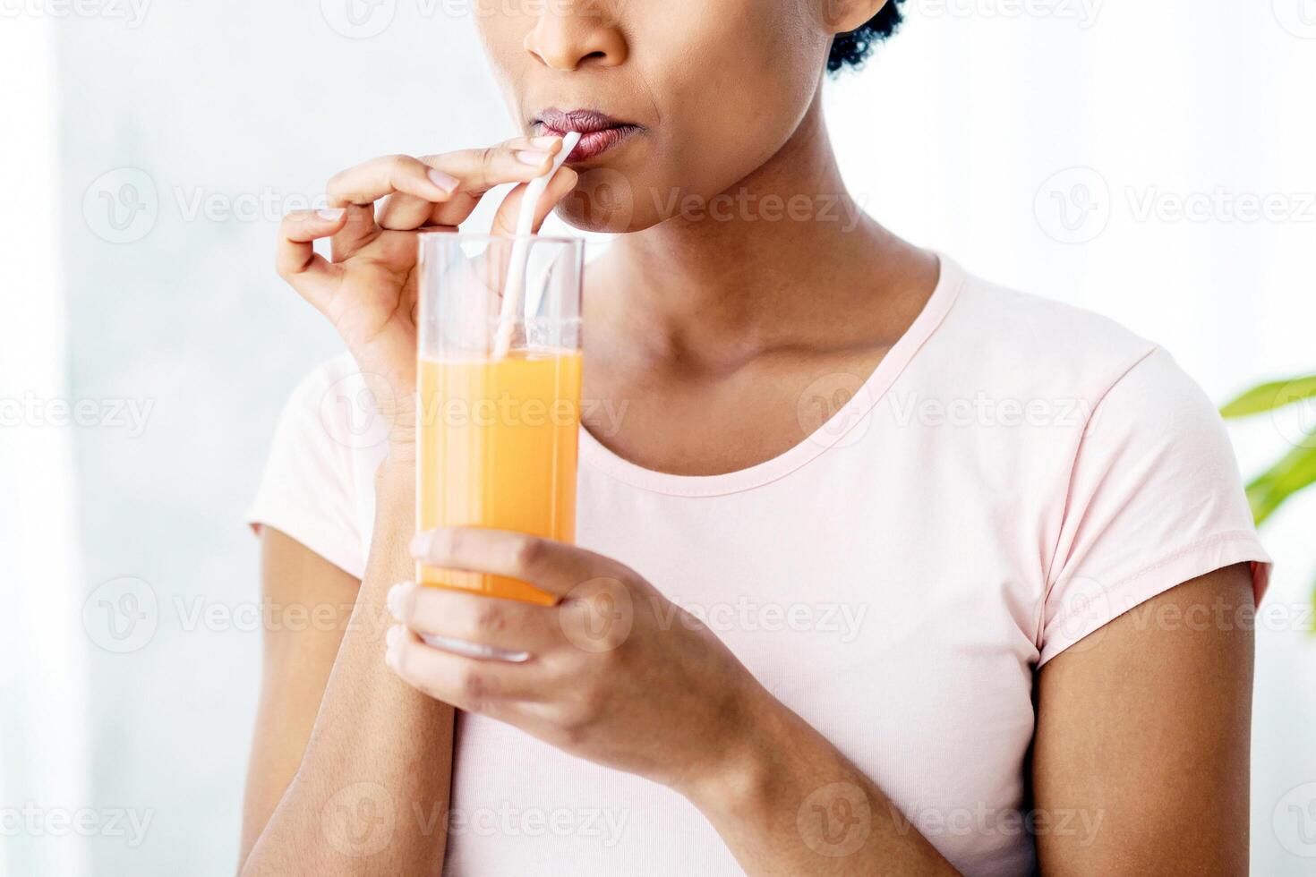 Pretty black woman drinking fresh orange juice at home, panorama. Slim African American lady having tasty fruit beverage indoors. Healthy living and detox concept photo