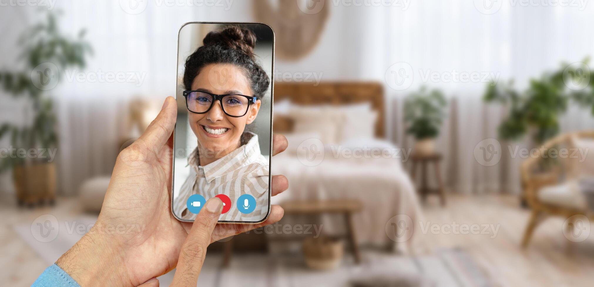A person holds a smartphone displaying a smiling individual on a call. photo