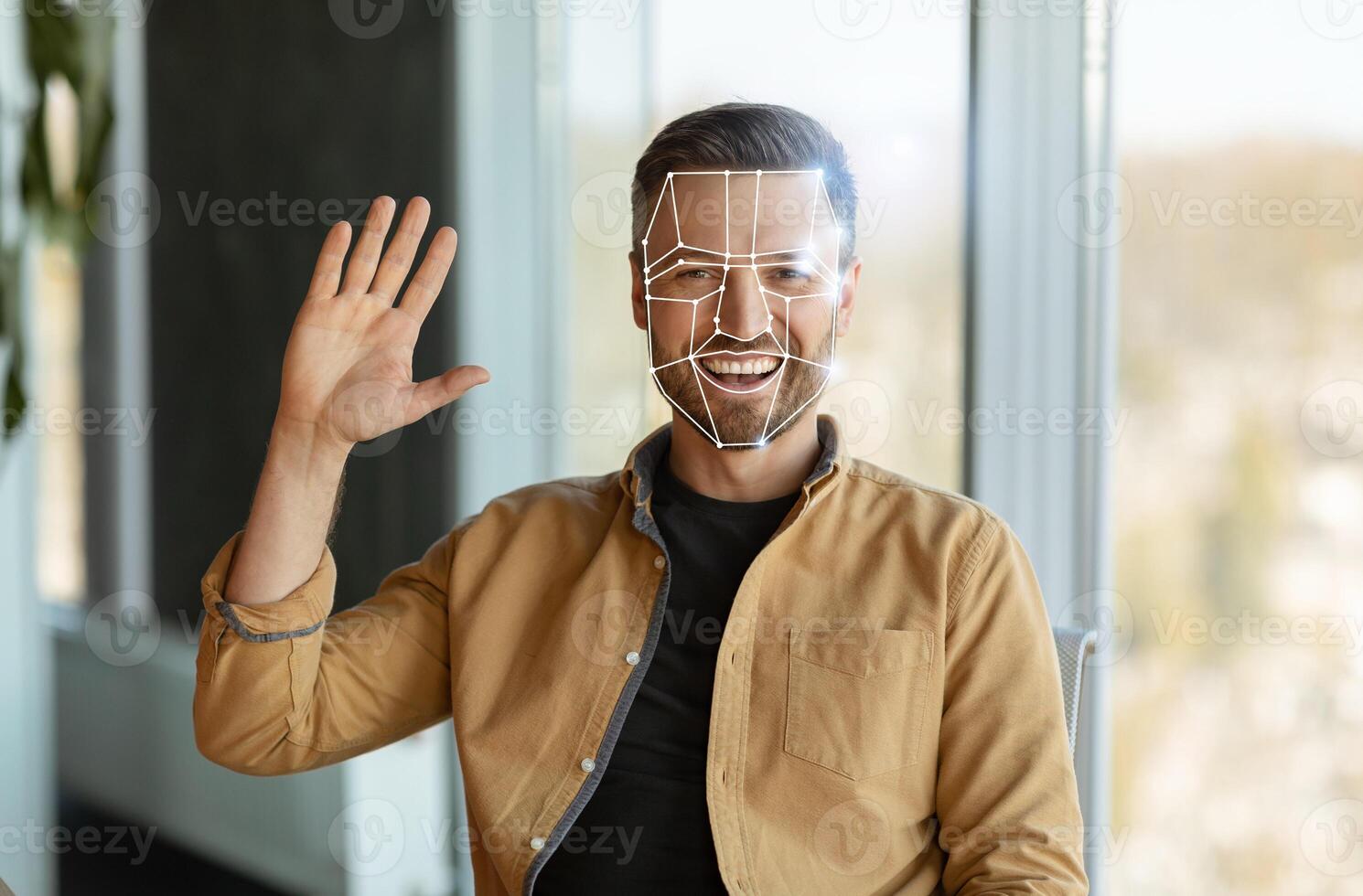 Man greets the camera while facial recognition technology analyzes his features. The setting reflects a contemporary office with natural light and greenery. photo