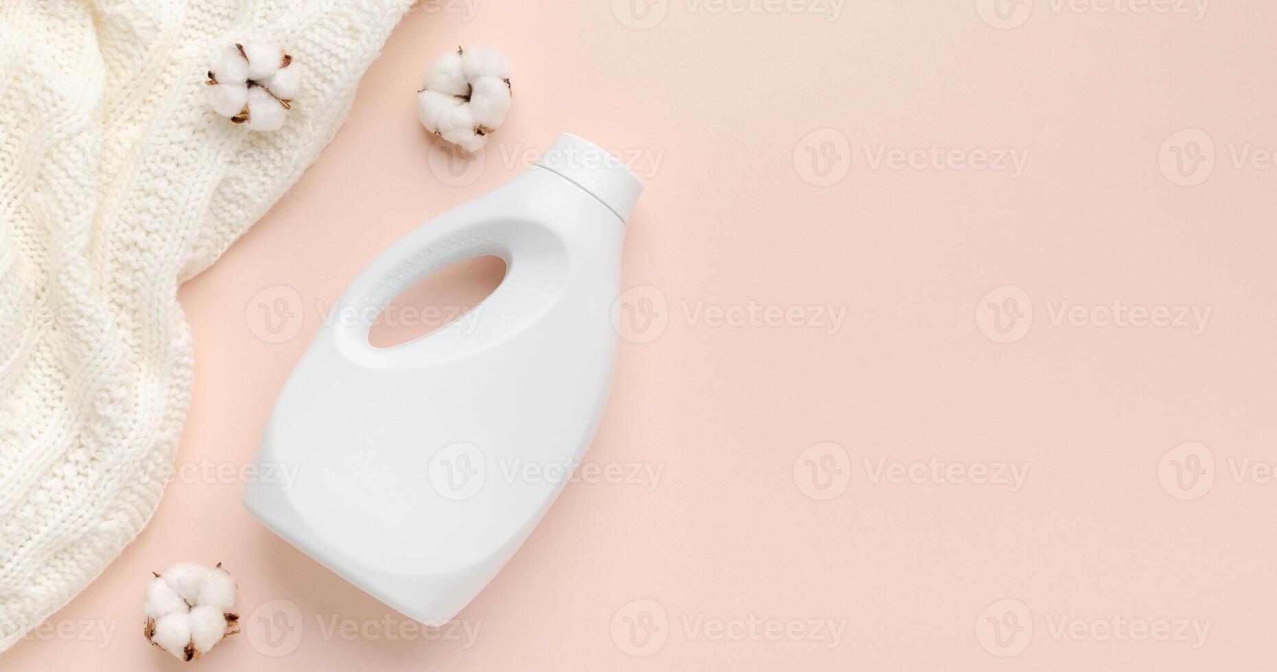 Liquid detergent bottle and white wool sweater. Fabric softener. Regular washing. Laundry concept. Empty place for text or logo on pastel pink background, panorama photo