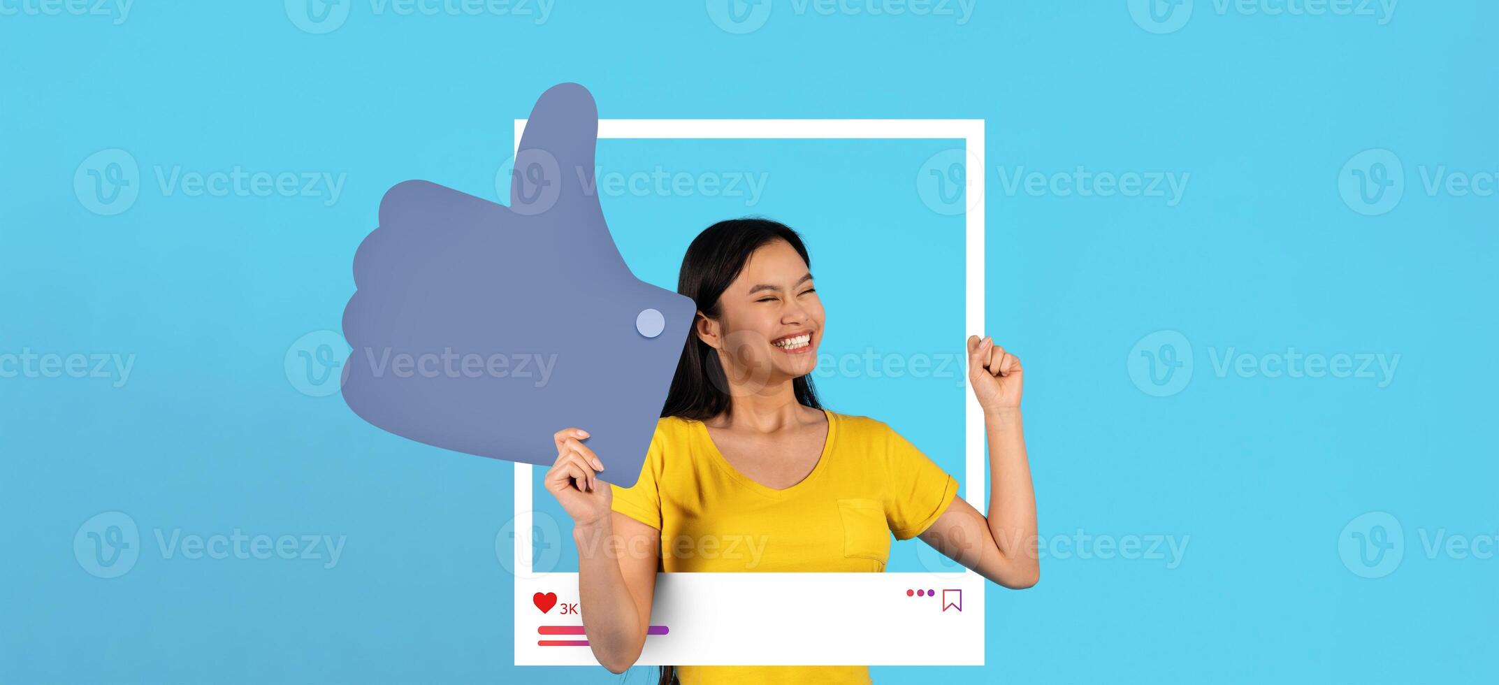 A young woman smiles brightly while posing inside a playful social media frame, holding a large thumbs-up sign. She radiates positivity, embodying the spirit of online content creation. photo