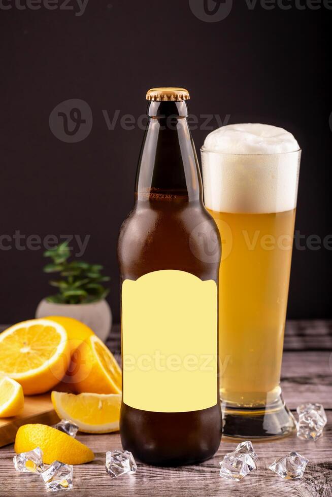 Cold beer bottle and foamy beer glass with lemon slices and ice cubes on rustic wooden table against black background. Ideal for summer drink ads, beverage branding or refreshing lifestyle promotions photo