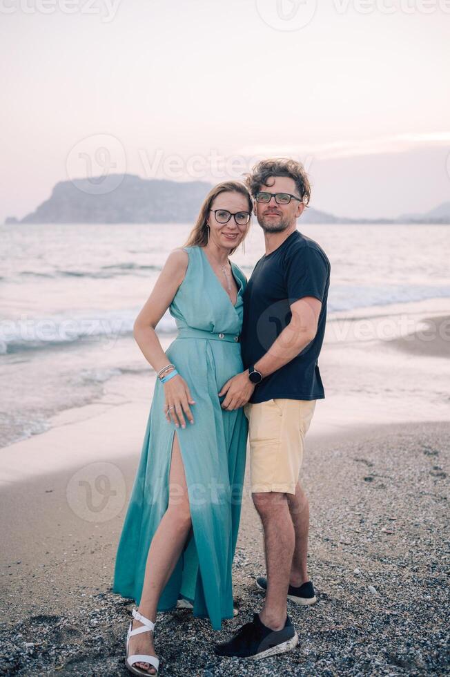 A smiling couple shares a joyful moment on the beach at sunset, the man and the woman near the sea waves, Alanya, Turkey photo