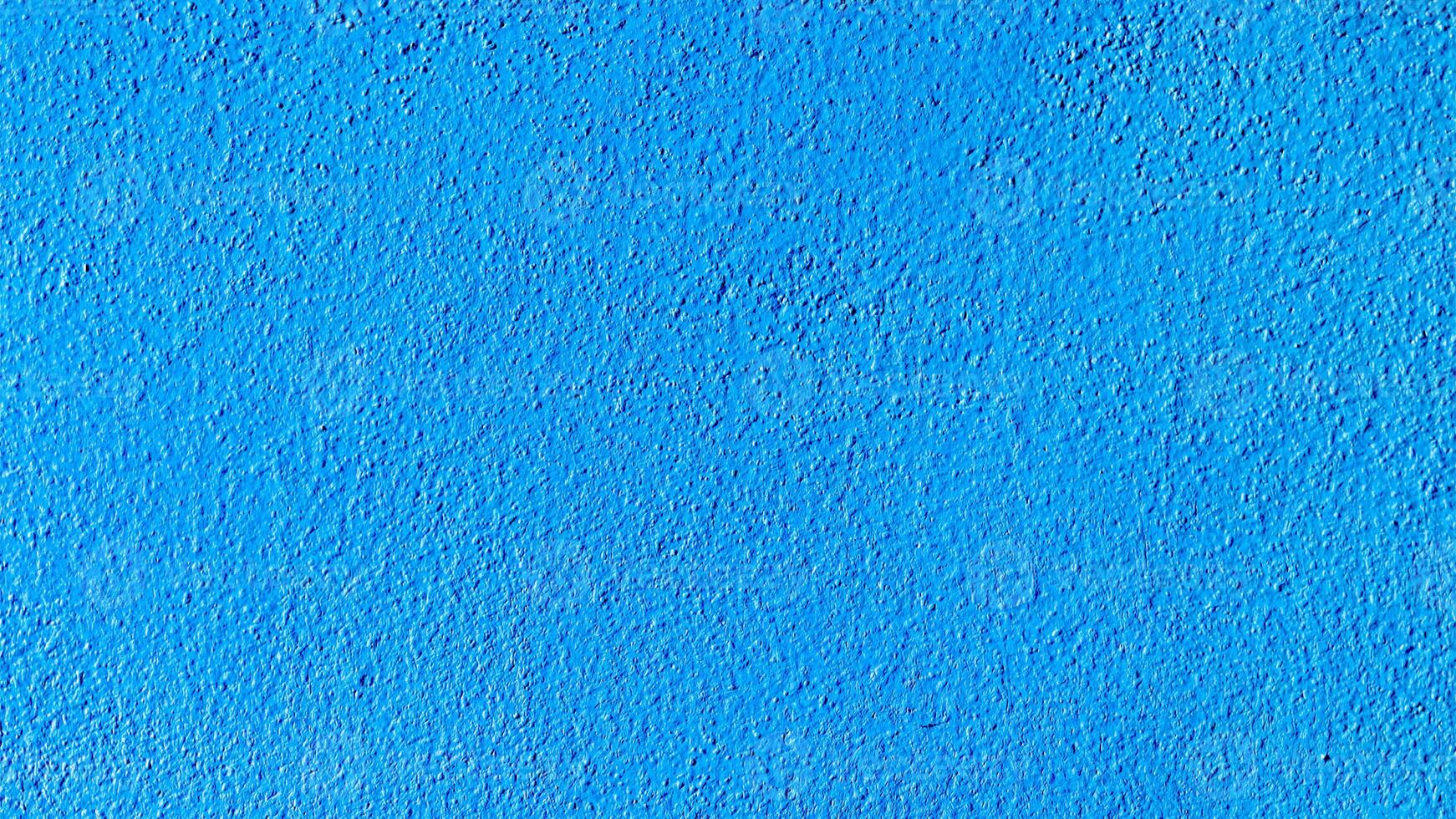 Bright Blue Textured Wall Surface with Subtle Shadows and Rough Finish for Background or Design Element photo
