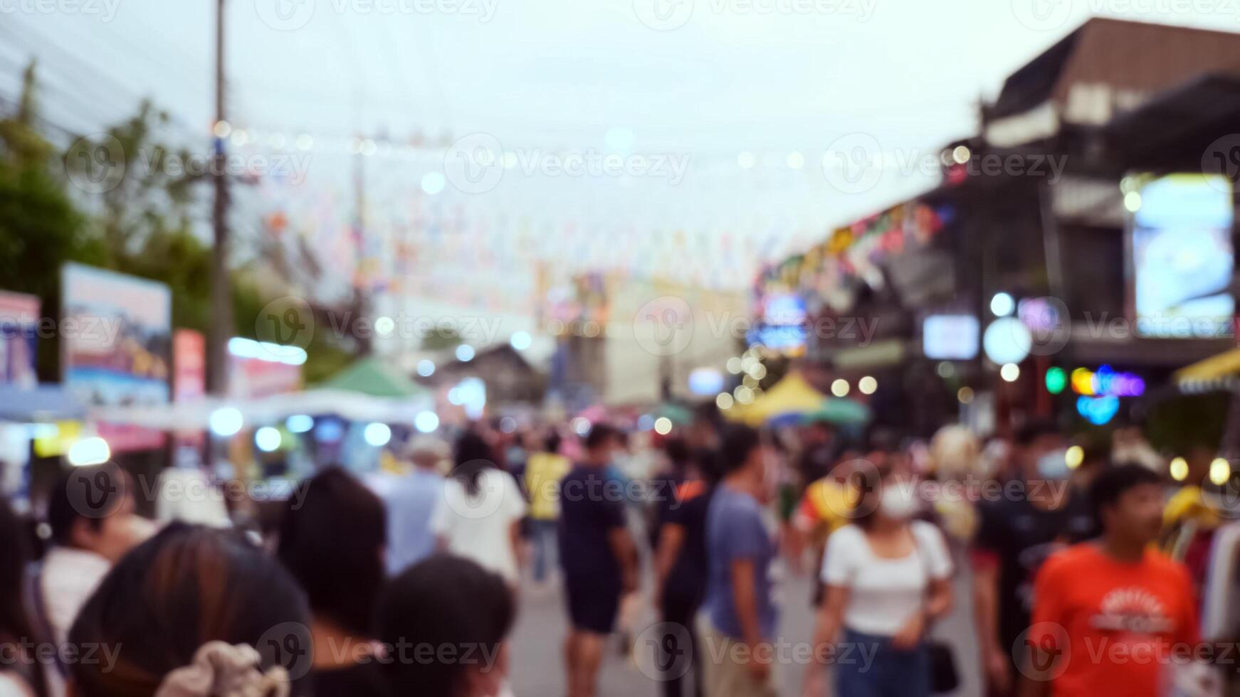 Blurred Image of a Busy Street Market with People and Colorful Decorations in the Evening photo
