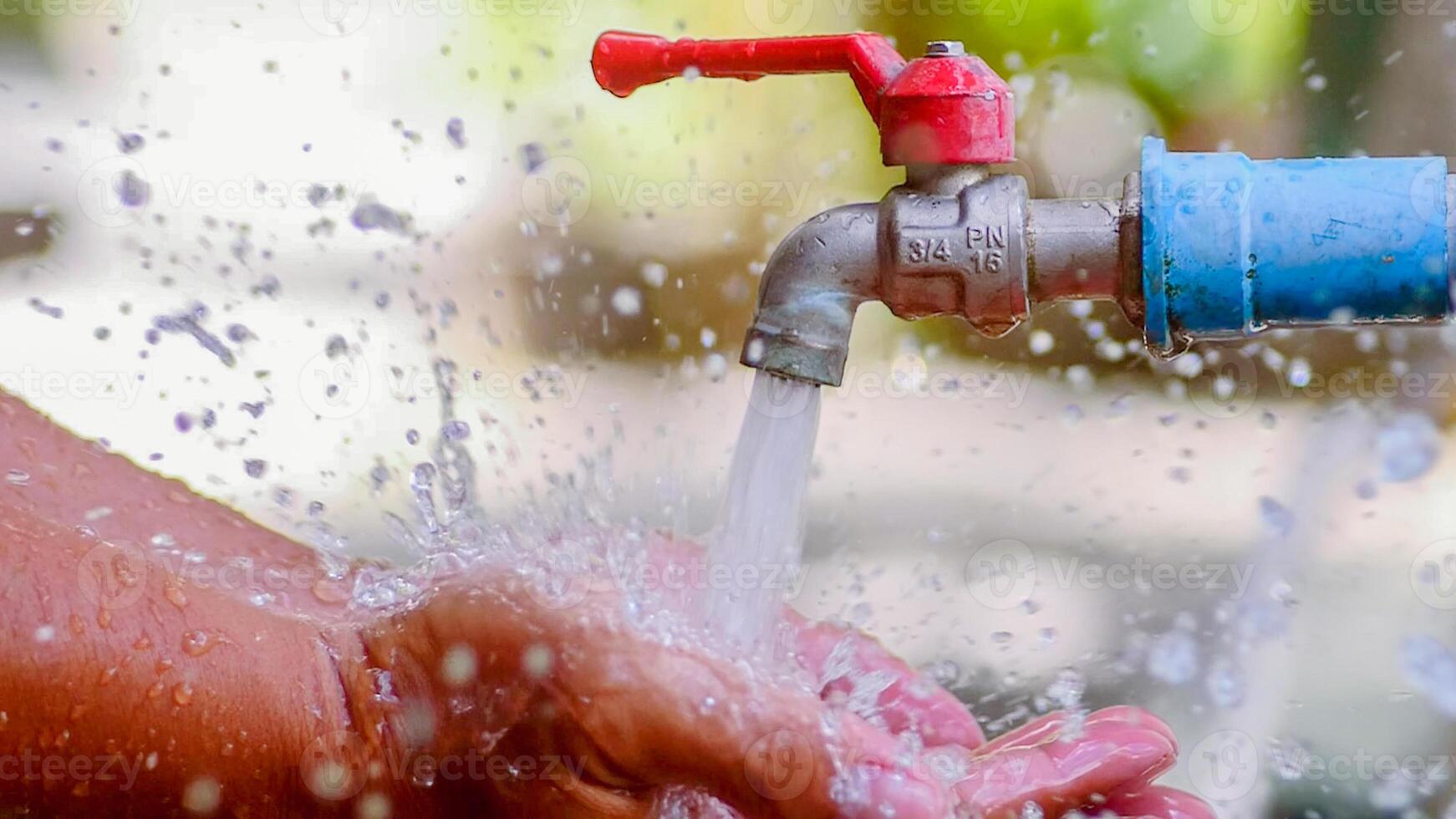 Close-Up of Hands Washing Under Running Water from Outdoor Faucet with Splashing Droplets in Daylight photo