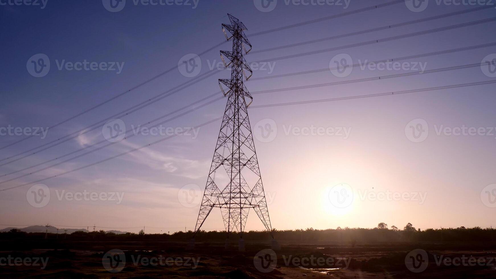 High Voltage Transmission Tower at Sunset with Clear Sky and Silhouetted Landscape in the Background photo