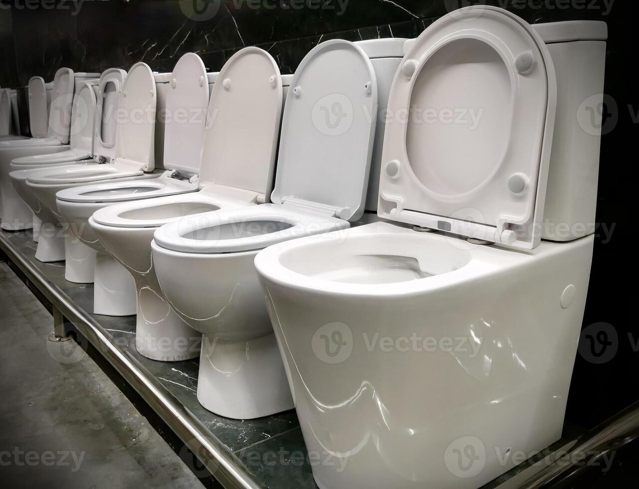 Modern white ceramic toilets displayed in a plumbing store showroom. Clean minimalist interior, suitable for construction, renovation, bathroom design photo