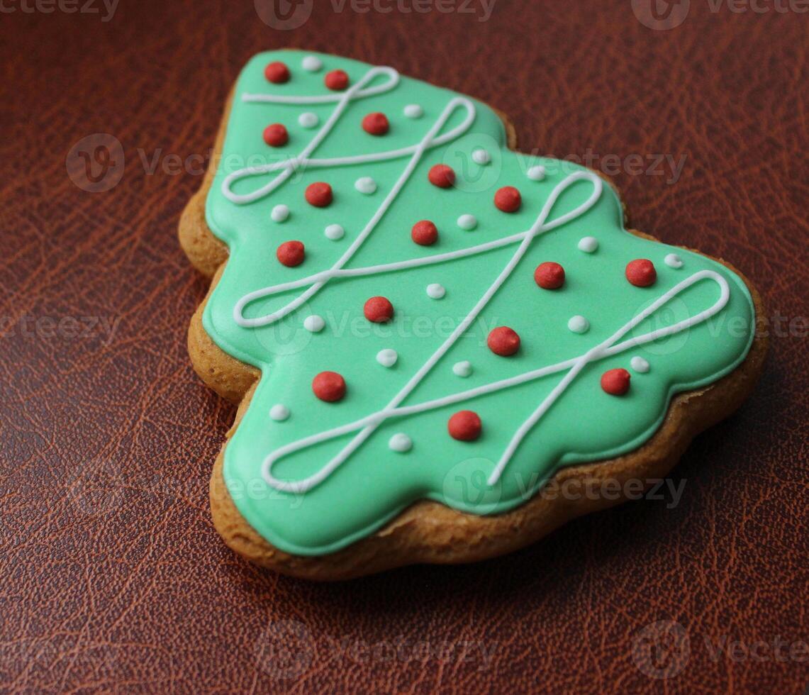 Traditional Christmas Tree Cookie Covered With Green Icing And Sweet Decor On Leather Surface Angle View photo