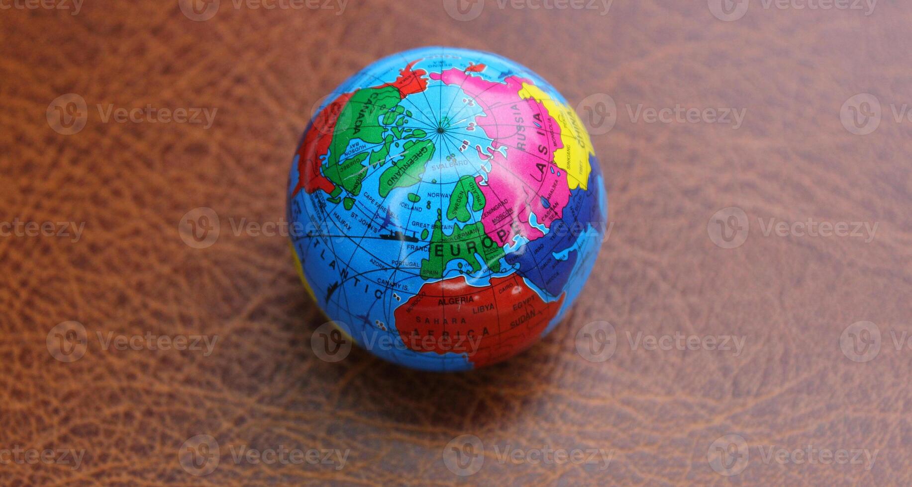 Miniature globe on a leather surface with conventionally drawn continents photo