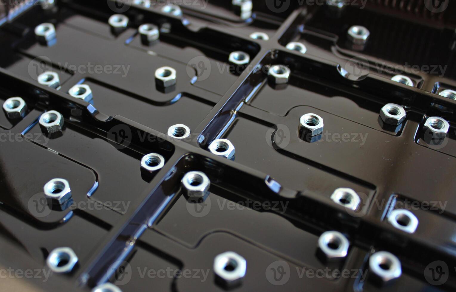 Separated Rectangular Elements With Screw Nuts On A Dark Varnished Plastic Panel photo