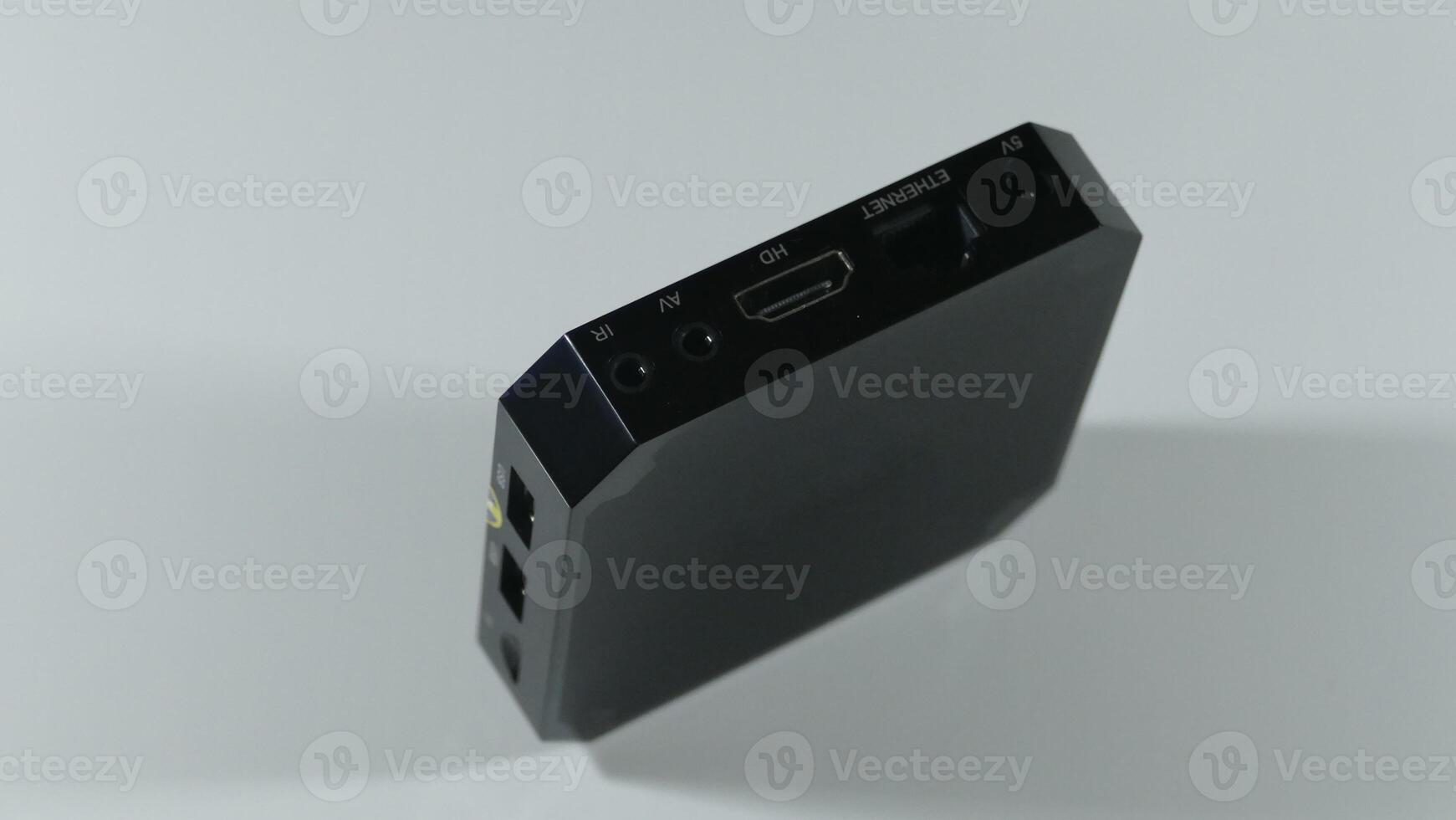 A square black TV tuner stands on an edge with visible slots and sockets for connection photo