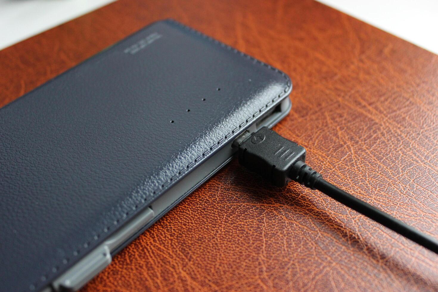 Elegant Leather Trimmed Power Bank Charging On Brown Leather Paper Folder Detailed Stock Photo
