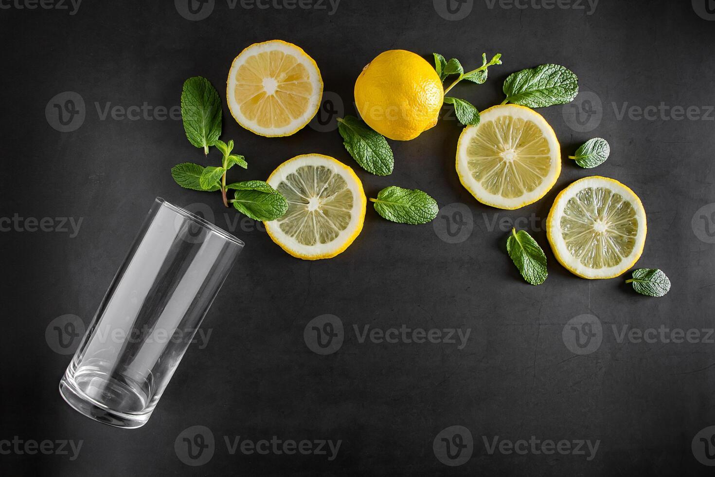 Fresh juicy lemon and mint leaves on black background. Ingredients for cocktail. photo