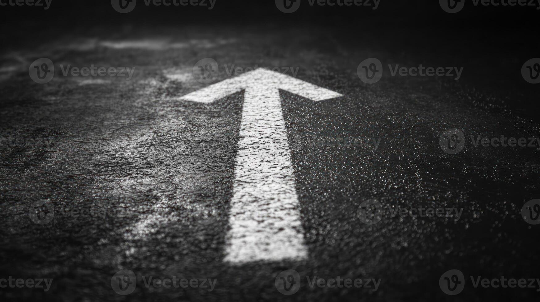 White arrow painted on dark asphalt road surface pointing forward symbolizing direction and progress in minimalistic style photo
