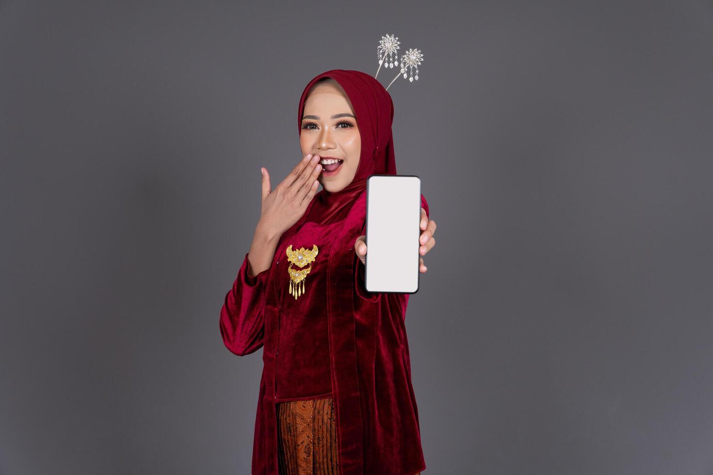 Young Asian Hijab Woman in Kebaya with Smartphone Smiling Background photo