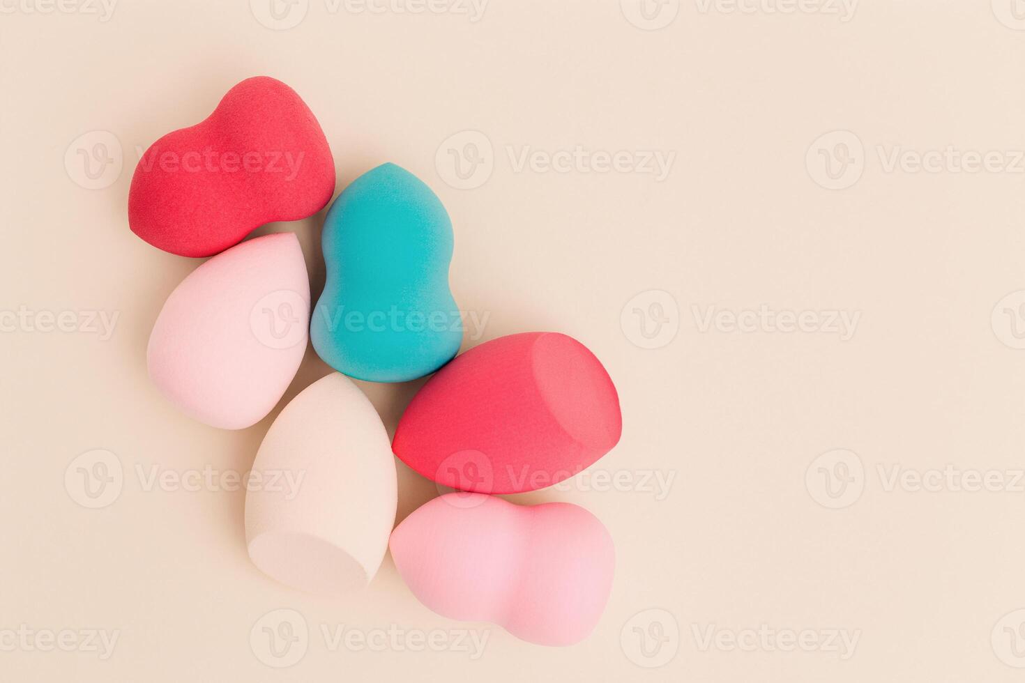 Colorful cosmetic beauty sponges close up different form on beige background with copy space. Top view, flat lay. photo