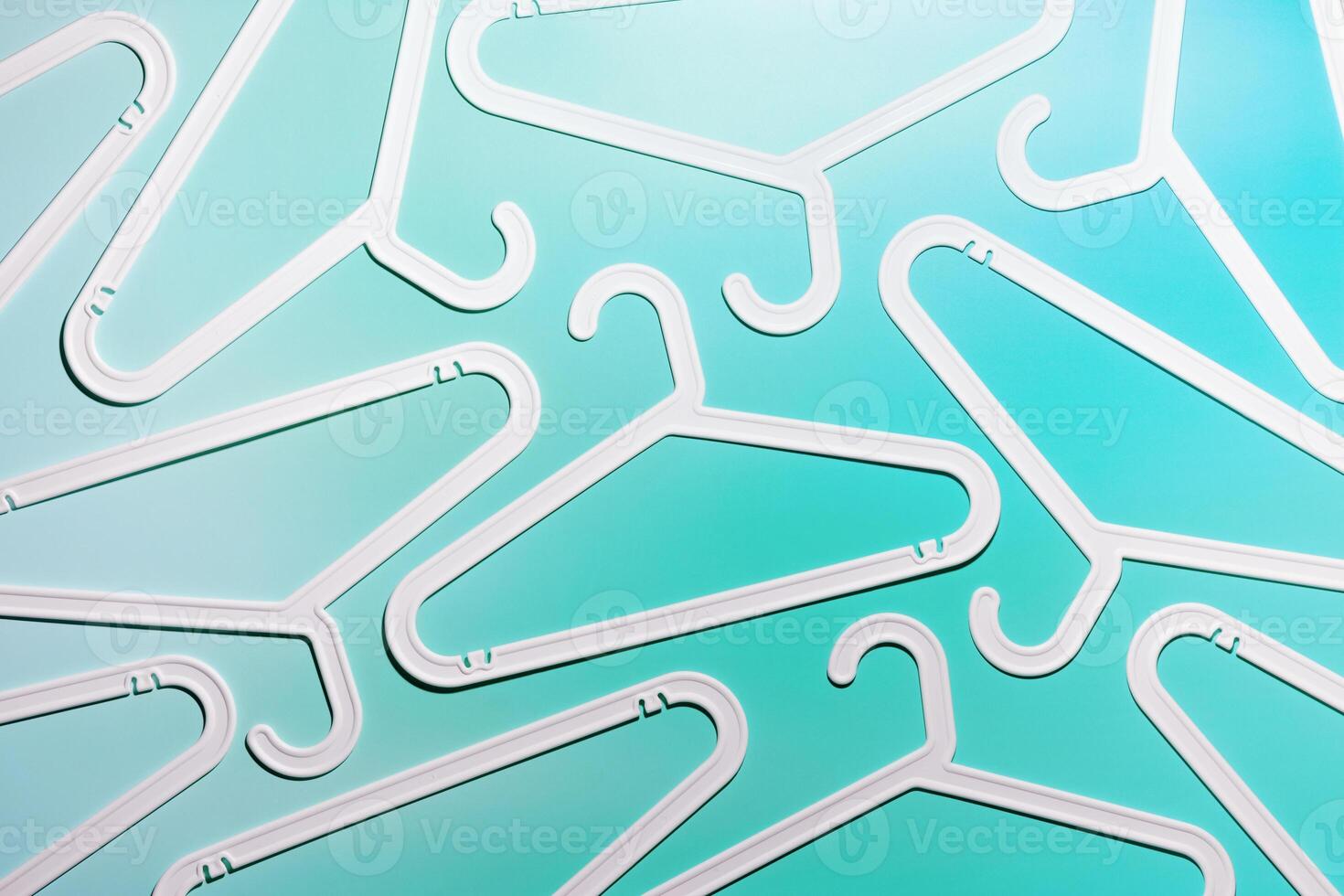White Clothes hangers as creative minimal composition on pastel teal gradient background, Plastic racks creating modern and geometric aesthetic, top view, flatlay creative photo, smooth lines pattern photo
