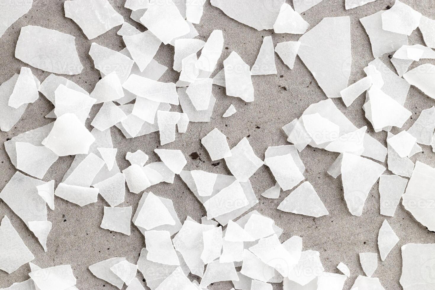 Closeup of Magnesium Salt Flakes on gray concrete background, detailed white particles sea salt, natural pattern Magnesium therapy, Health Benefits, self-care, promoting wellness, home relaxation photo