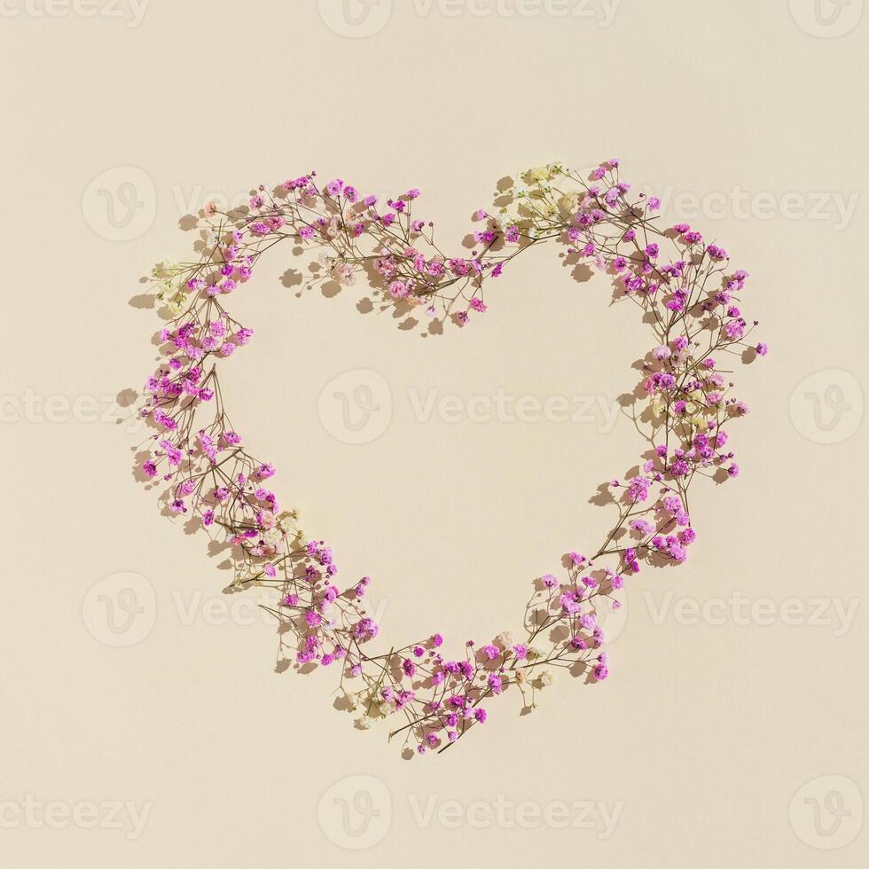 Small pink flowes on beige color. Narural frame in shape of heart. Minimal style aesthetic card for wedding invitation photo