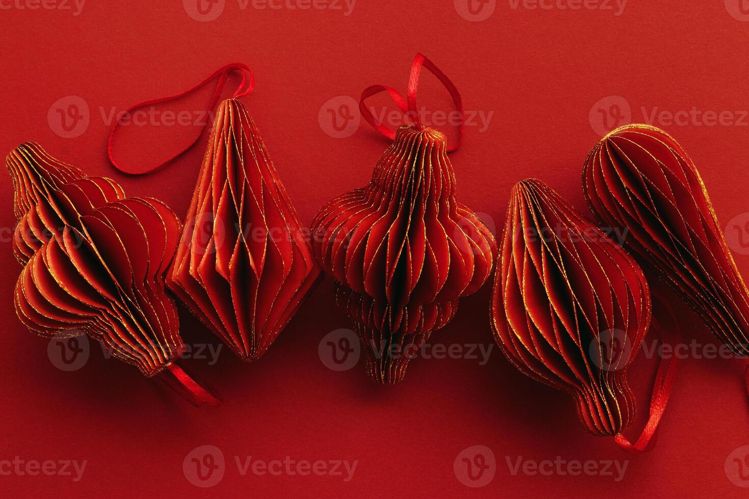 Shiny Red Paper Christmas Ornaments, winter seasonal holiday decorations on red background, copyspace, Happy New Year holiday minimal backdrop, vivid dark color. Top view handmade Christmas bauble photo