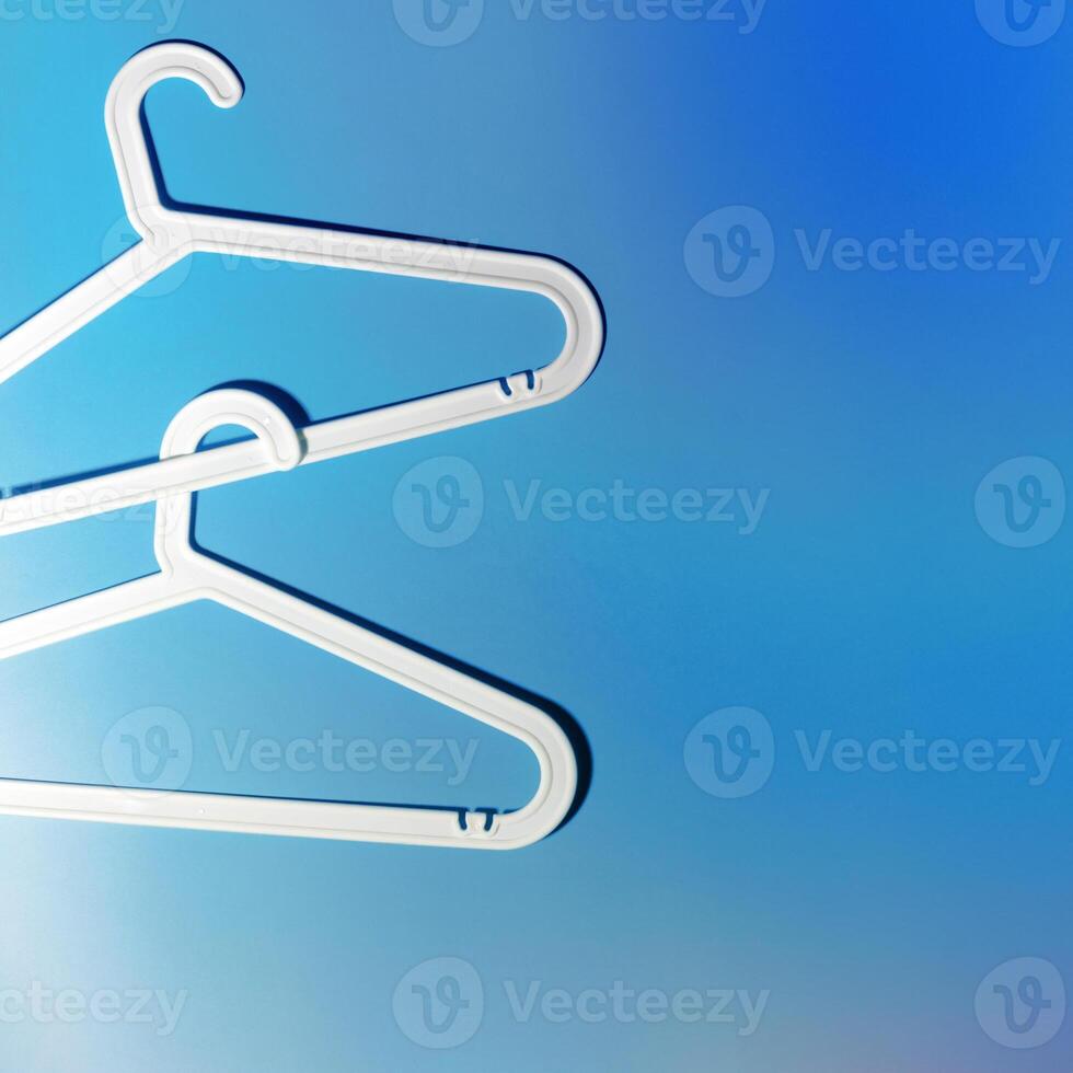 Top view White Plastic hangers, minimal style layout on white blue gradient background, Clothes rack for organizing clothes in closets or retail stores, fashion, organization concept, copyspace photo