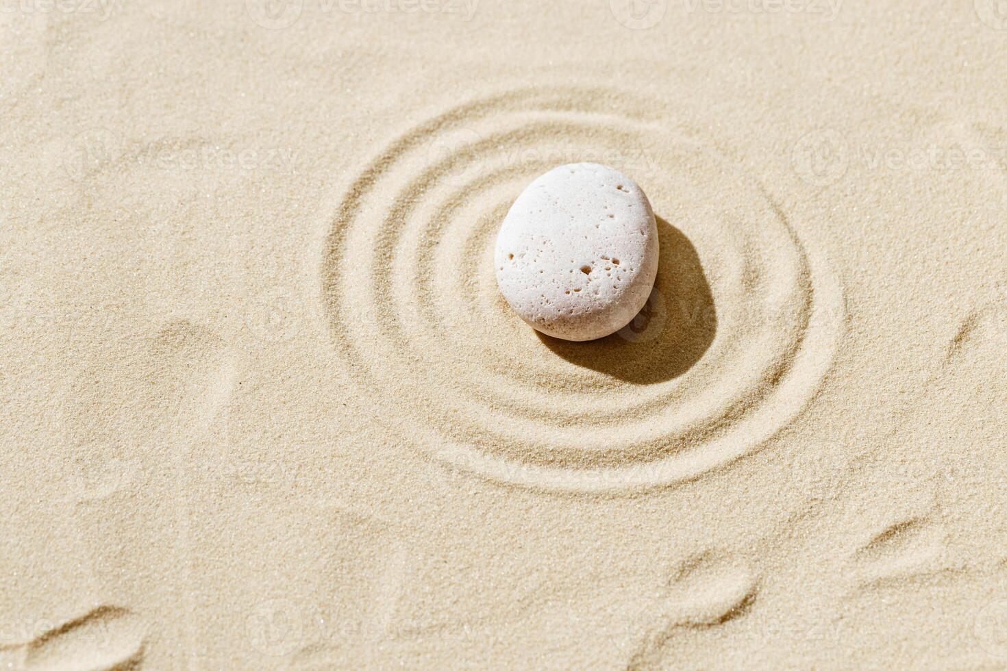 Aesthetic minimal background with zen stone on sand. Japanese Zen Garden with concentric circles around stone cairn. photo