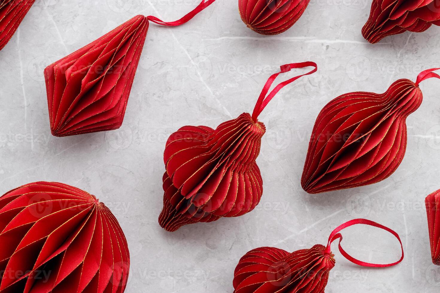 Red Christmas paper baubles as shape Lantern on marble grey table, Scandinavian Christmas honeycomb ornaments. New year paper decor, modern xmas decoration, minimal winter holiday above pattern photo