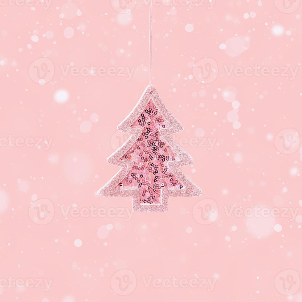 Minimal Christmas and New Year greeting card with pink toy Christmas tree with shiny sequins on pink photo