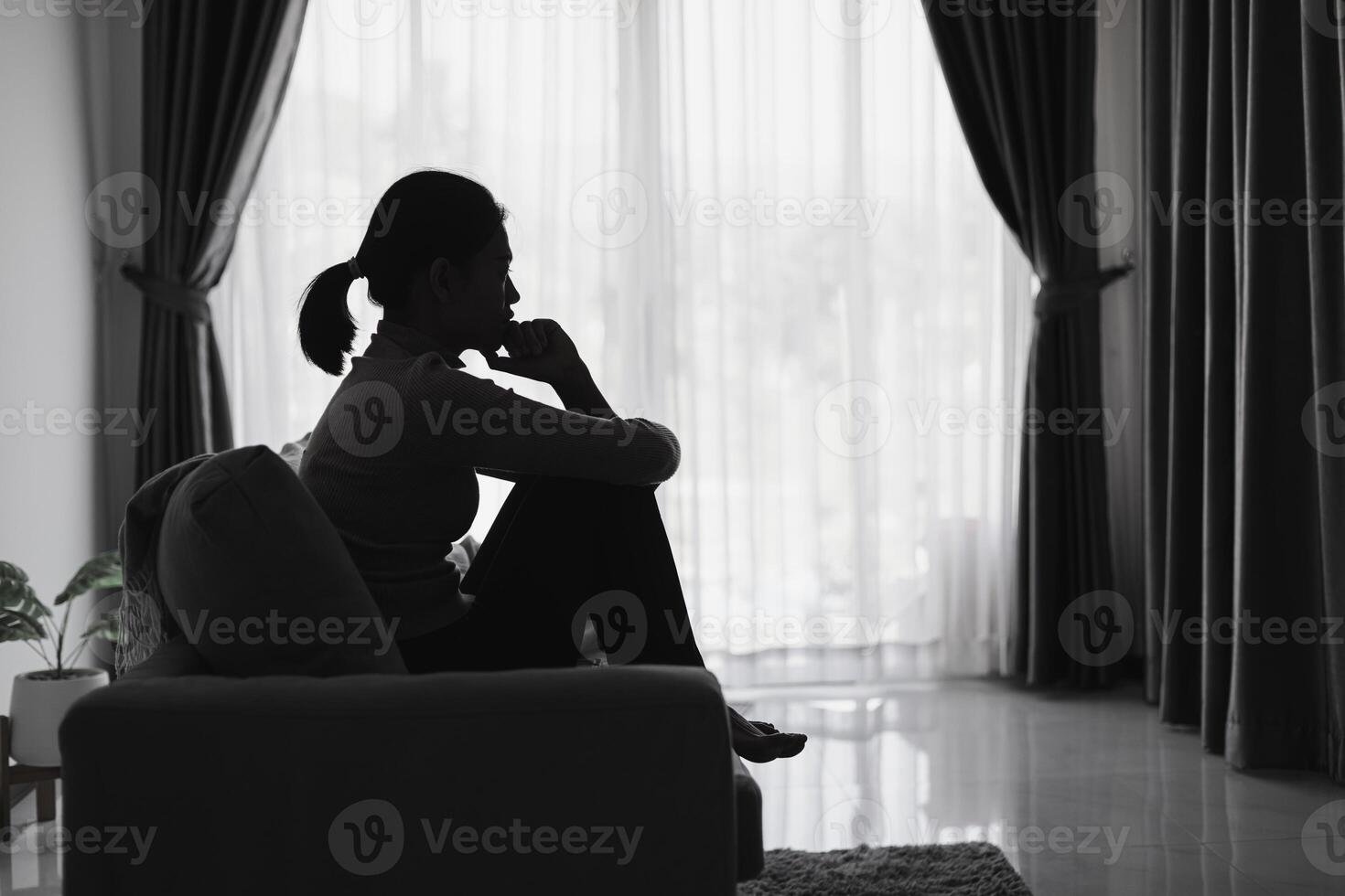 A depressed woman sits on a sofa. photo