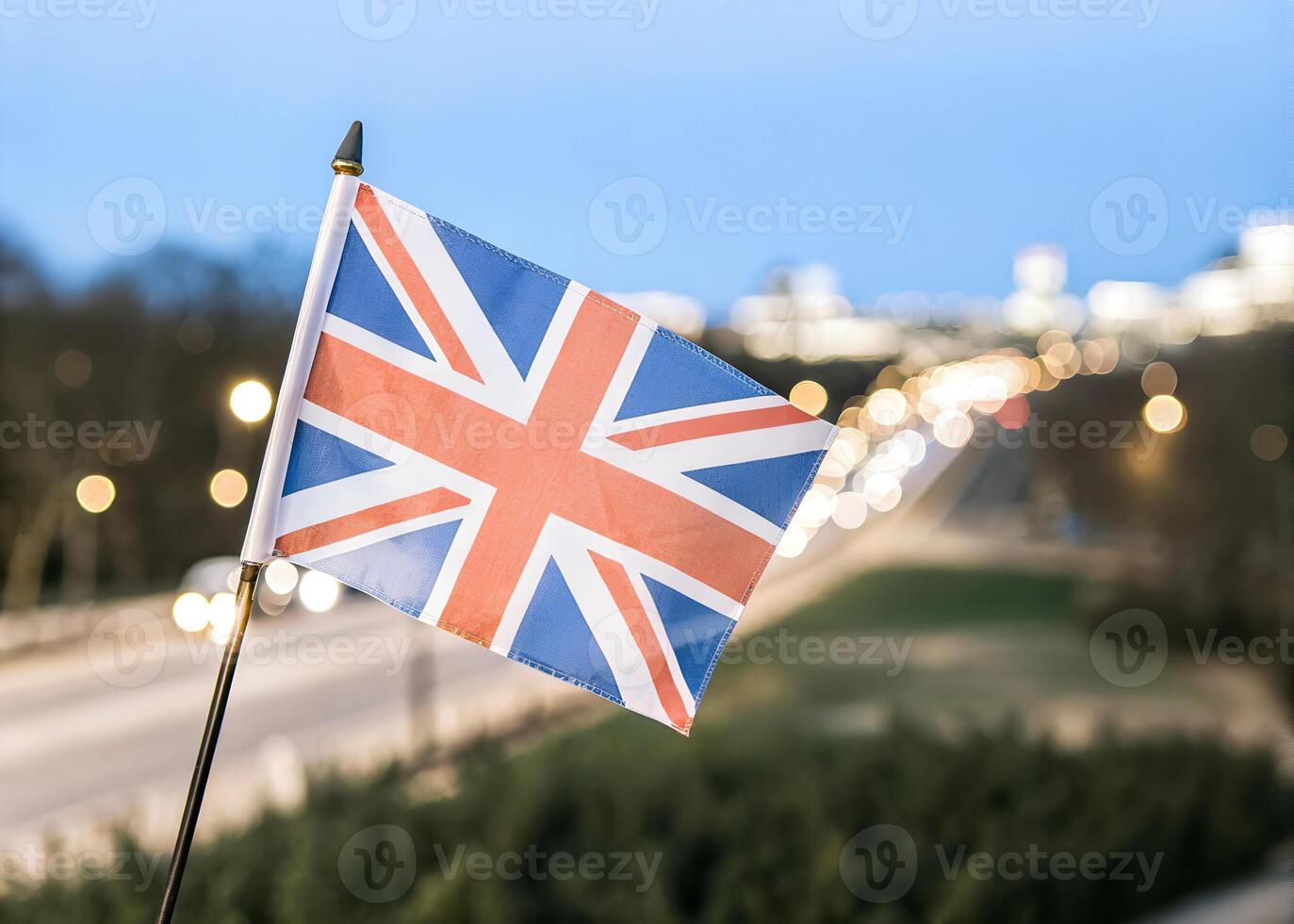 Close-up, United Kingdom Flag Waving in the Wind. Evening background, In the capital of United Kingdom, city lights and road photo