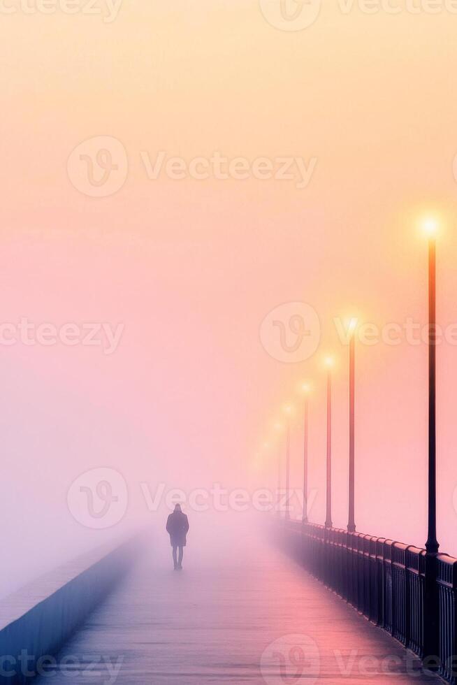 A solitary person strolls across an empty bridge as fog envelops the area during twilight photo