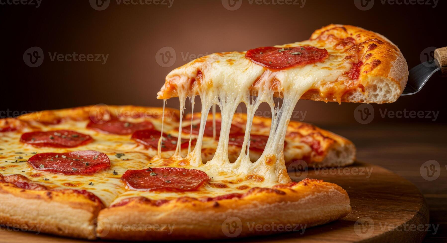 Hot pepperoni pizza with oozing cheese being lifted on serving slice photo