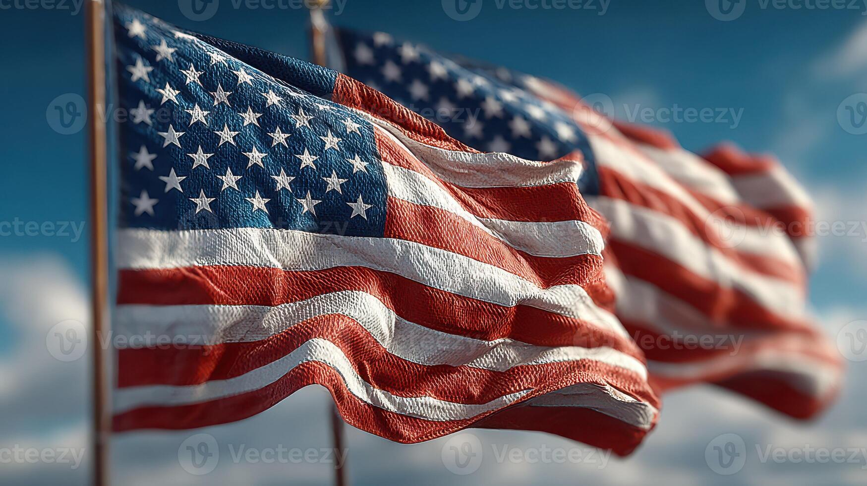 Waving American flags flutter in the wind against a bright blue sky during a sunny day in a park photo