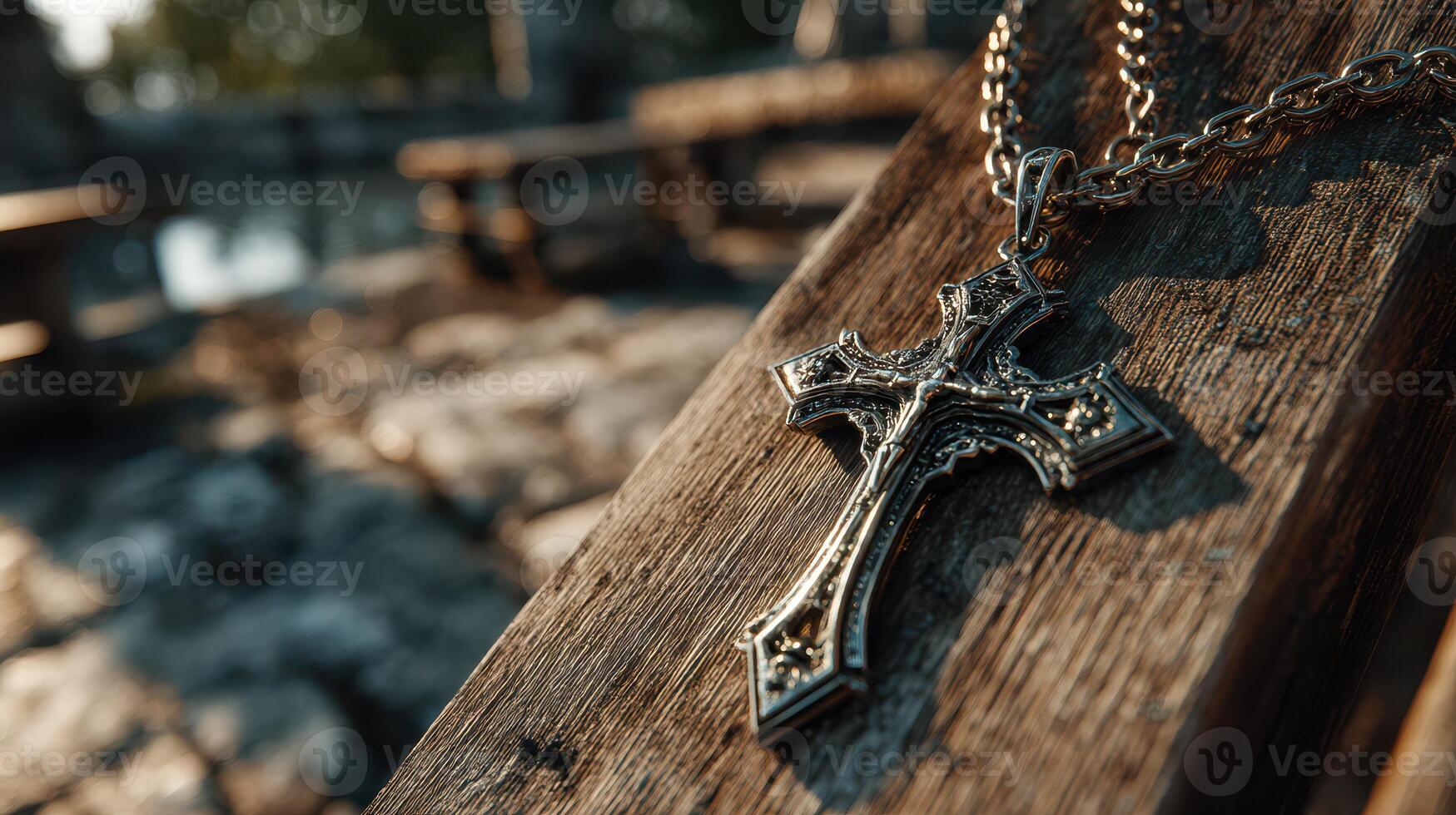Cross necklace resting on weathered wood near water at sunset showcasing intricate design and reflections photo