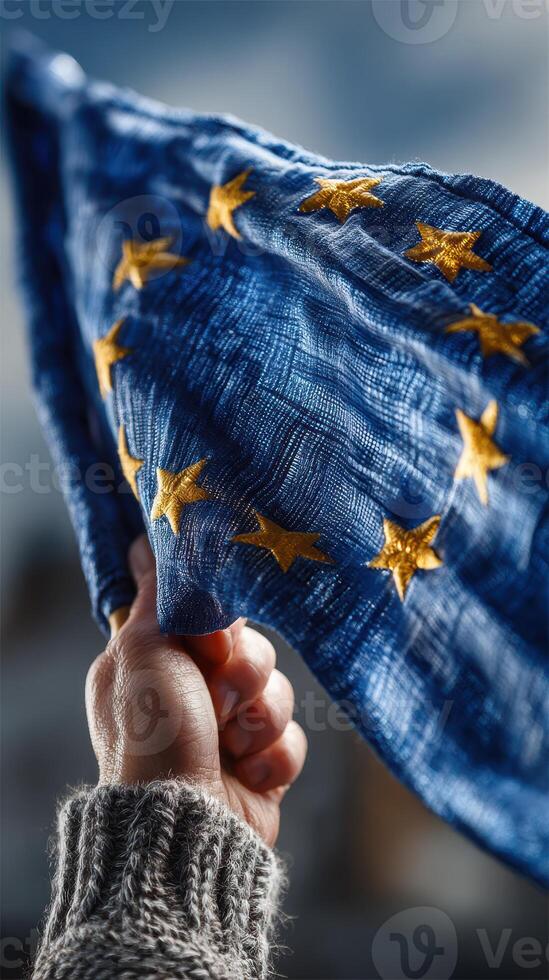Person holds European Union flag against cloudy sky, showcasing unity and support for Europe during a public rally photo