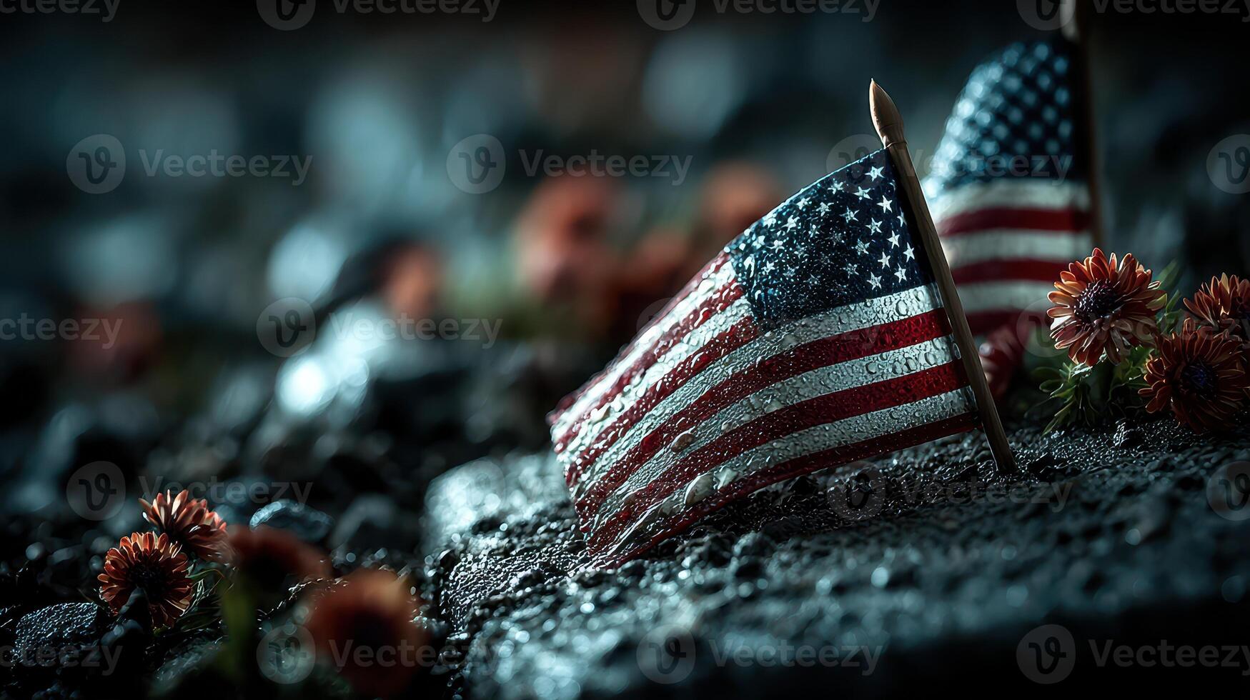 Small American flags placed on a rocky surface adorned with flowers during an evening commemoration event photo