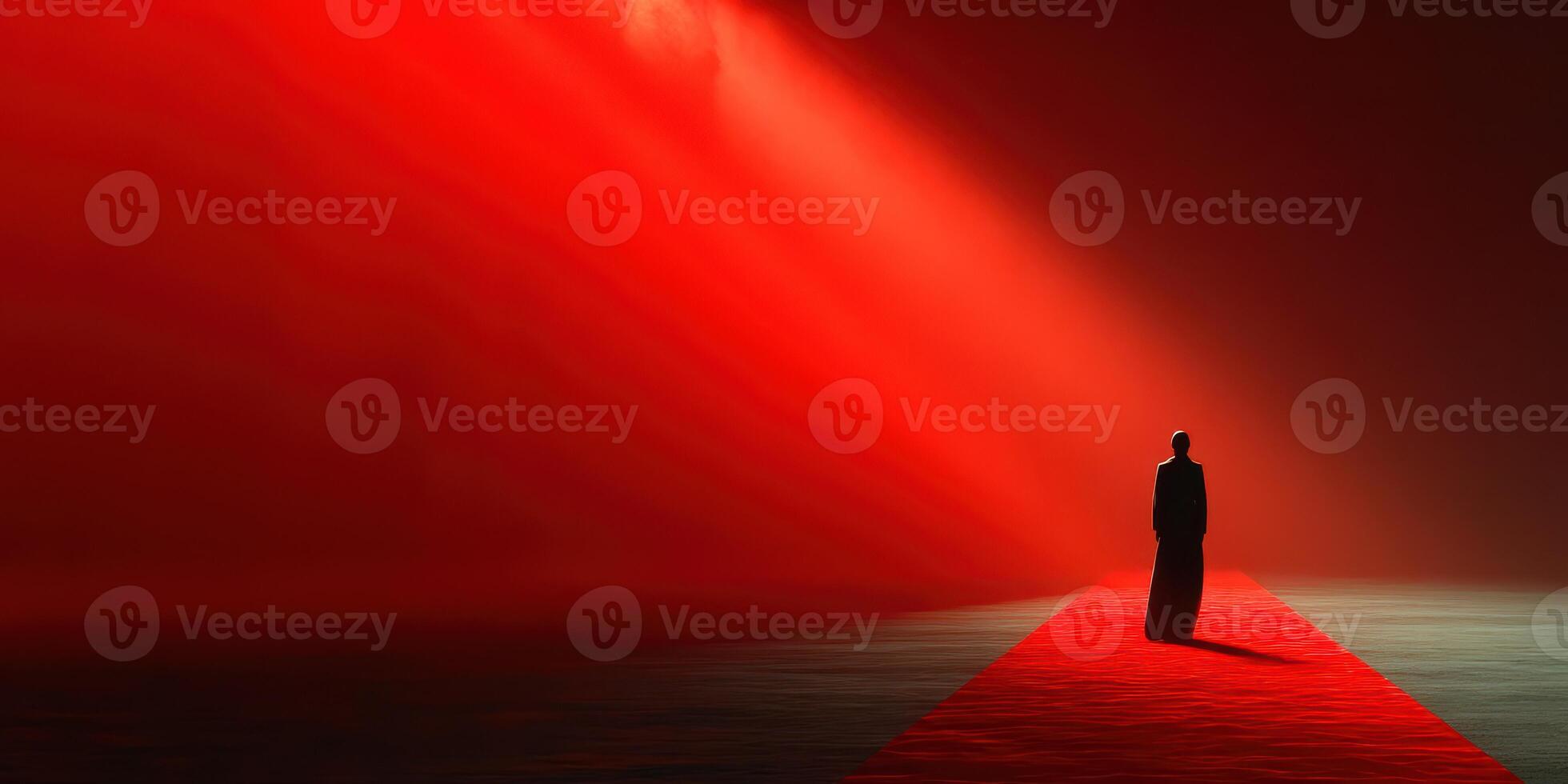 Individual stands on red carpet under dramatic lighting in a minimalistic setting during a festive event photo