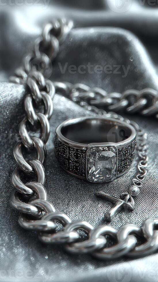 Silver jewelry collection featuring a diamond ring and chain on a textured surface with soft lighting photo