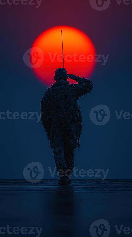 Soldier saluting at sunset with vibrant red orb setting on the horizon photo